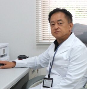 白衣を着たスタッフが医務室で医療機器の前に座っている